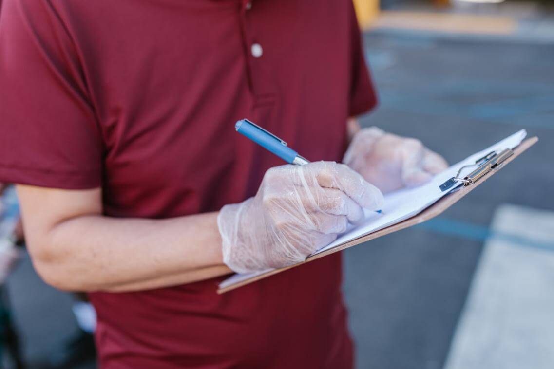 a person in maroon taking notes, representing a guide to conducting a trash audit